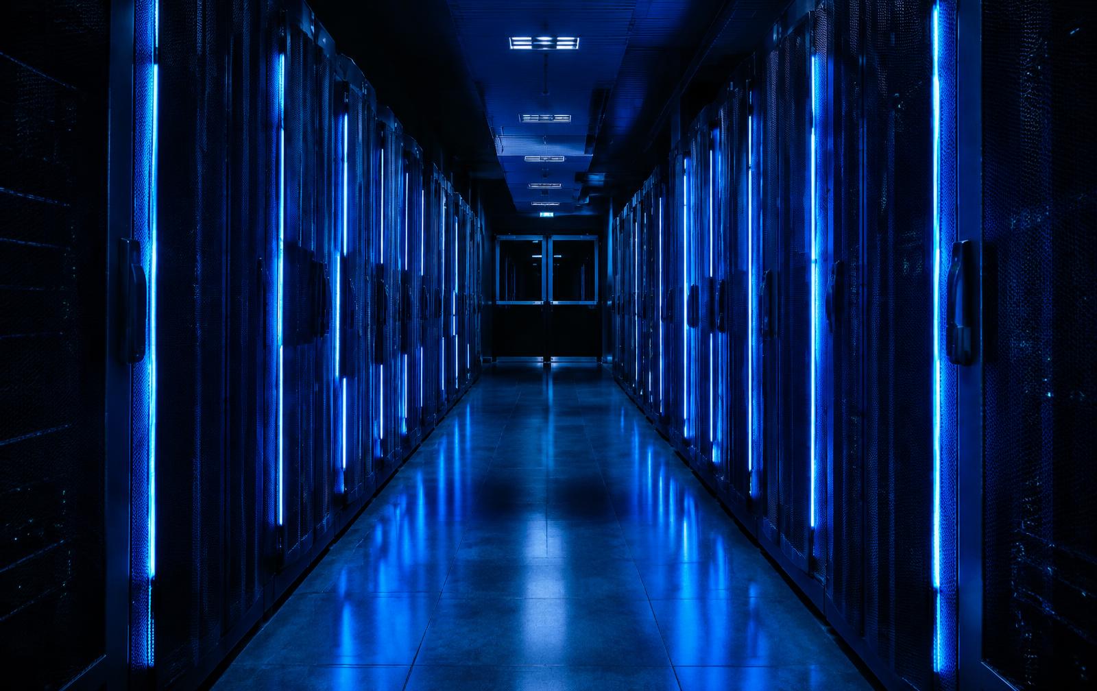 Server racks lit in cobalt blue along a data center corridor